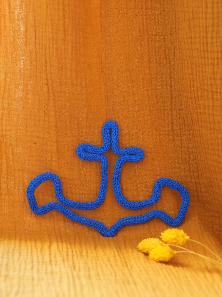 ancre en tricotin bleu sur tissu orange avec fleurs jaunes en décoration